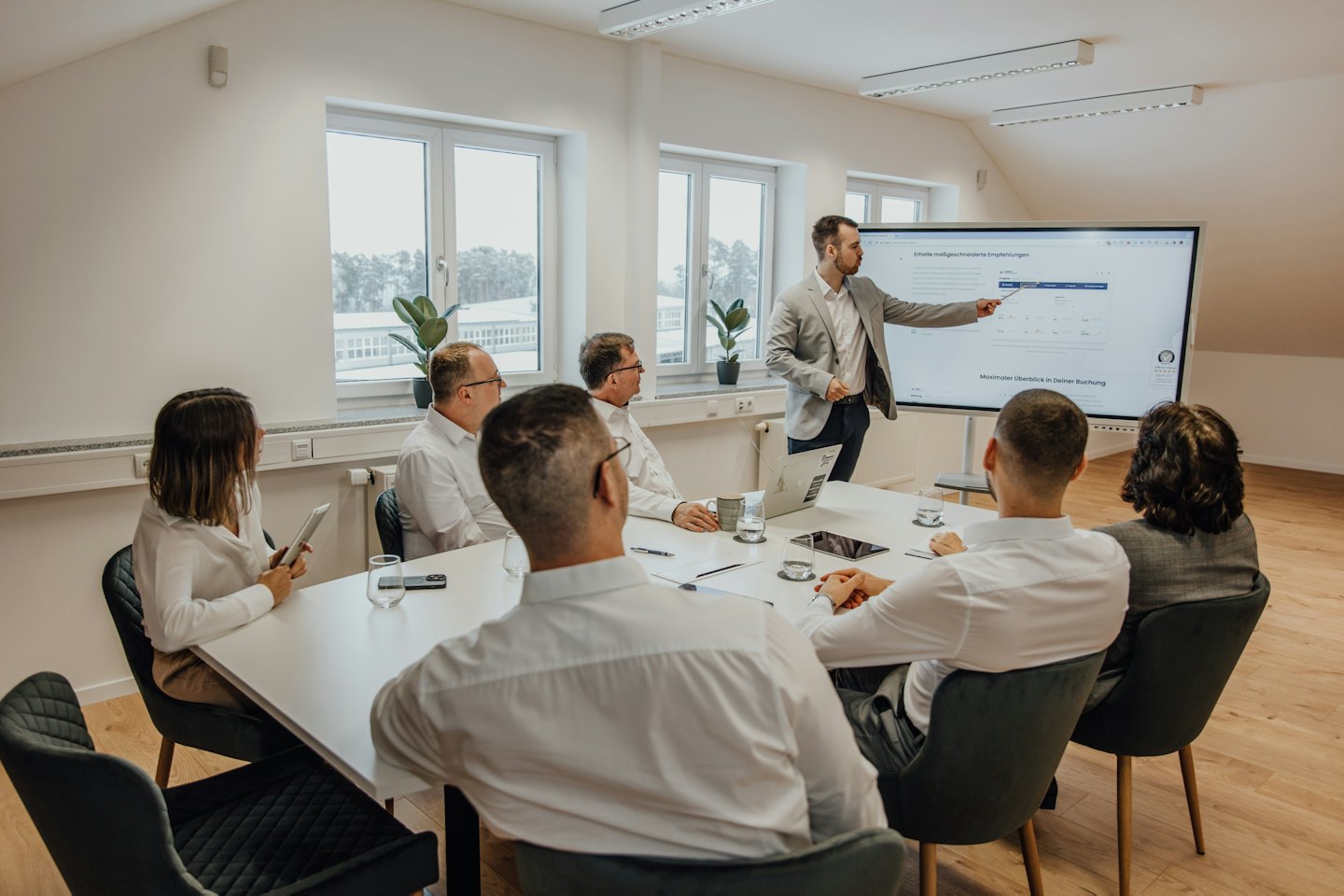 Business professional presents data on a screen to colleagues in a meeting.